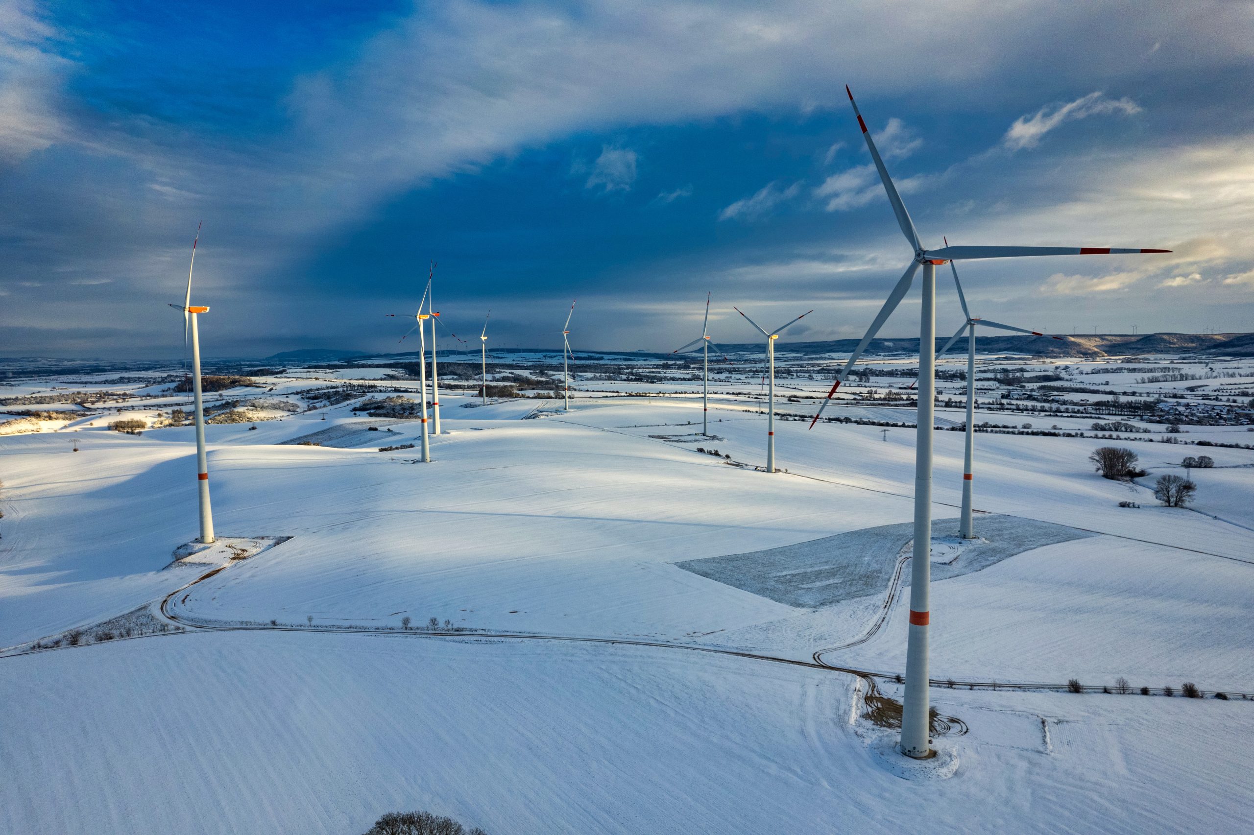 Drone shot of wind turbines in late afternoon light in flat snowy northern German landscape